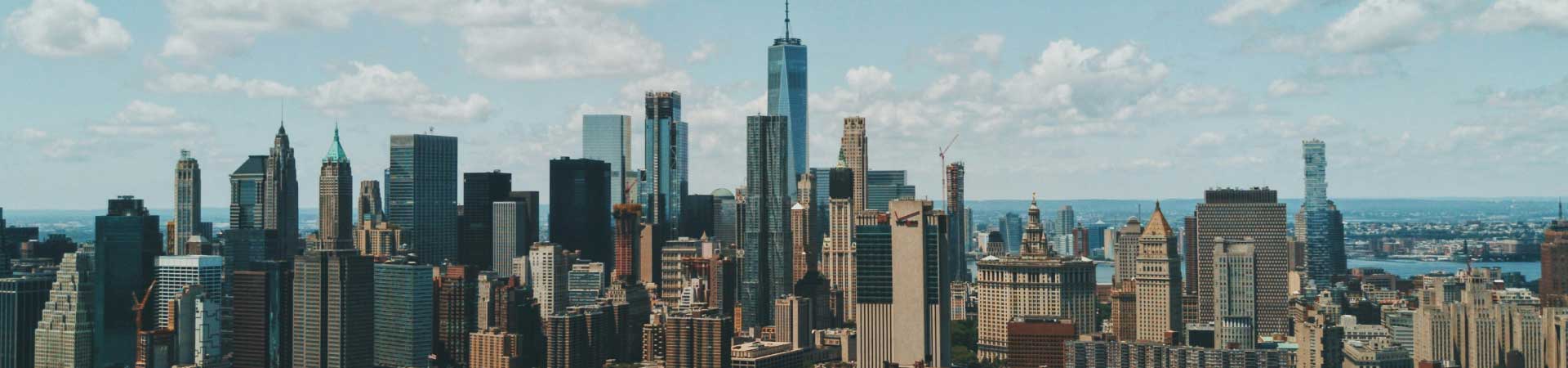 ნიუ-იორკის სკაილაინი One World Trade Center-ით ცისფერი ცისა და ღრუბლების ფონზე