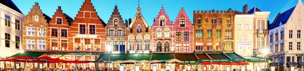 ფერადი სახლები ბრიუგეს მოედანზე ღამის განათებით კაფეების ფონზე