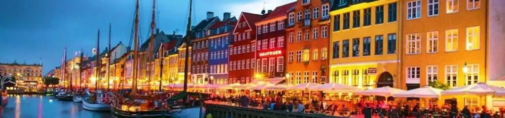 ნიუჰავნის უოტერფრონტი კოპენჰაგენში ფერადი სახლებითა და გემებით ღამის განათებით