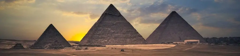 გიზის პირამიდები მზის ჩასვლის დროს ოქროსა და ლურჯი ცის ფონზე