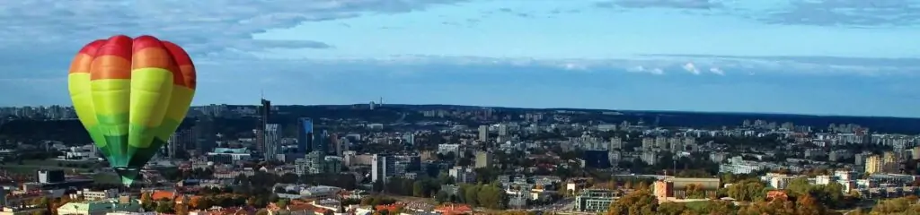 ფერადი საჰაერო ბურთი ქალაქის პანორამის წინ ცისფერი ცის ფონზე