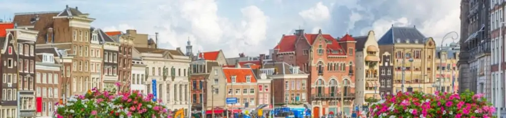 ამსტერდამის ფასადები ყვავილებით ღრუბლიანი ცის ფონზე