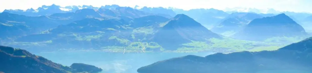 ალპების პანორამული ხედი - მთები, ტბა და მწვანე ველები