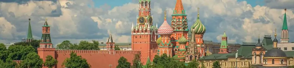 მოსკოვის კრემლისა და წმინდა ბასილის ტაძრის პანორამული ხედი, ფონზე მწვანე ხეებითა და ღრუბლებით